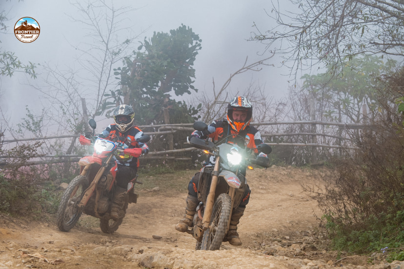 Vietnam motorcycle tour rider riding through a remote mountain road under changing weather conditions